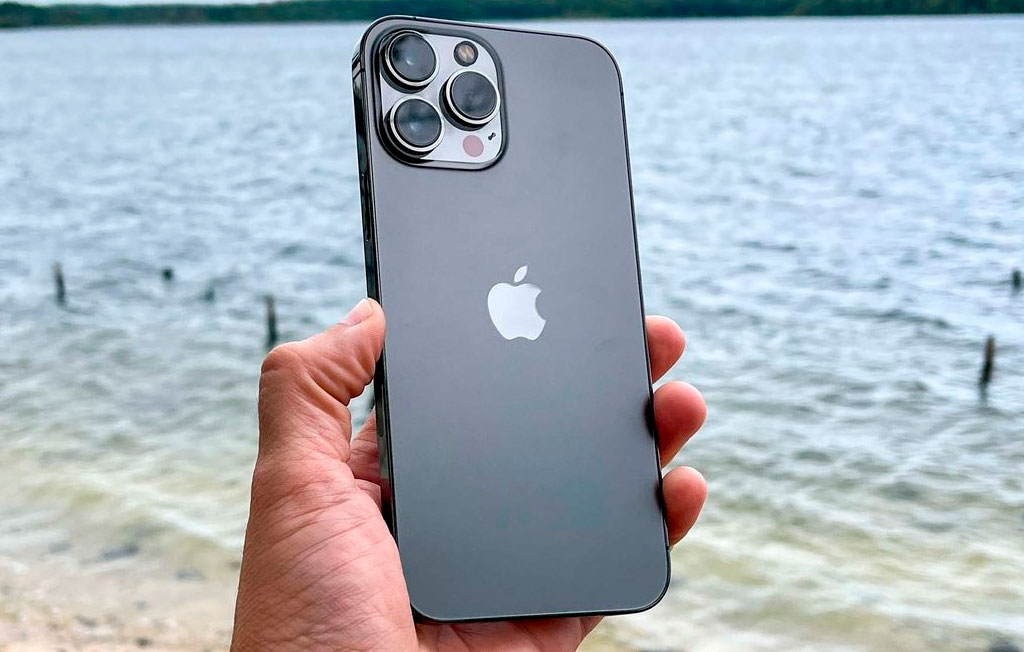 گوشی iphone 13 pro max در دست کنار دریا